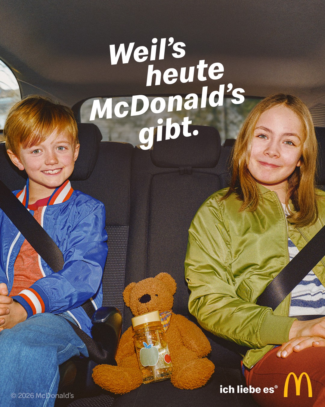 Kampagnenmotiv für die McDonald’s-Kampagne „Weil’s heute McDonald’s gibt.“ Zwei Geschwister sitzen auf dem Rücksitz eines Autos und lächeln irritierend brav nach vorn.